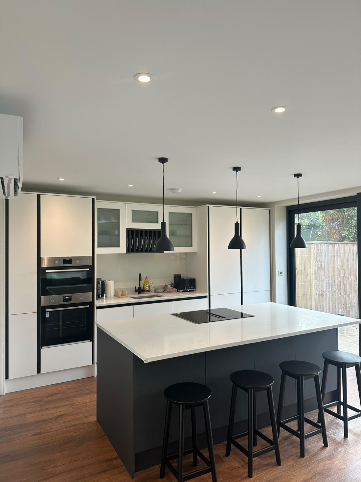 Modern open-plan kitchen with matched black dome pendants over a large island and recessed LED downlights — domestic kitchen lighting installation by D.P.L Electrical Services in Oxfordshire